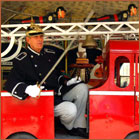 Feuerwehrmann in historischer Uniform auf Feuerwehrwagen im Kinderkarussel